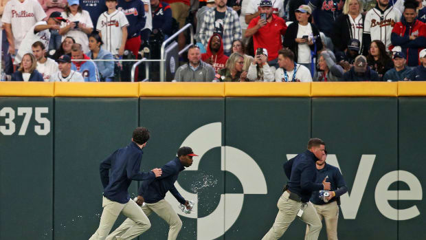 Braves grounds crew members pick up objects thrown on the field during Atlanta's NLDS opener against the Phillies on Oct. 7, 2023.