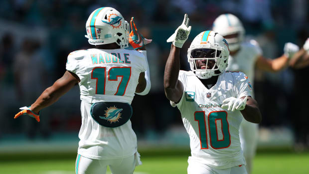 Tyreek Hill puts his hand up toward Jaylen Waddle’s as the two jump in celebration