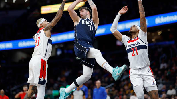 Nov 15, 2023; Washington, District of Columbia, USA; Dallas Mavericks guard Luka Doncic (77) leaps to pass the ball as Washington Wizards forward Kyle Kuzma (33) and Wizards center Daniel Gafford (21) defend in the first quarter at Capital One Arena. Mandatory Credit: Geoff Burke-USA TODAY Sports