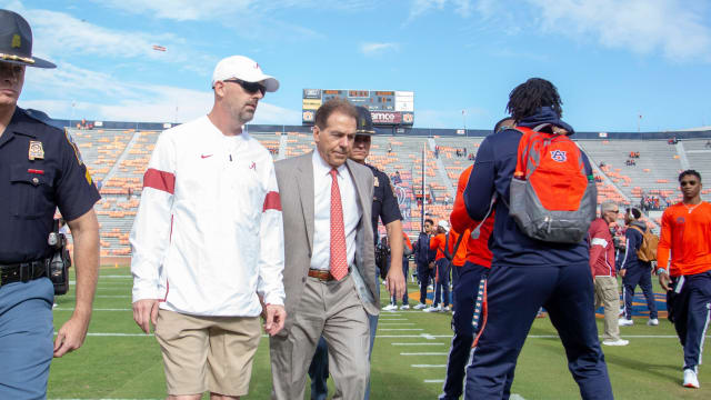 Alabama head coach Nick Saban is escorted across the field as Auburn players get pumped up around him. Iron Bowl 2019