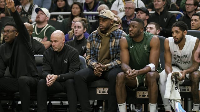 Milwaukee Bucks forward Khris Middleton sits on the bench in street clothes 