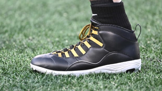 A detailed view of Derek Carr's black and gold Air Jordan cleats.
