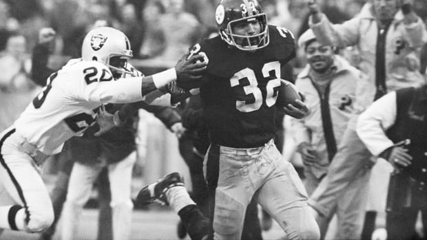 Franco Harris eludes a tackle by Oakland Raiders’ Jimmy Warren as he runs 42-yards for a touchdown after catching a deflected pass during an AFC Divisional NFL football playoff game in Pittsburgh on Dec. 23, 1972.