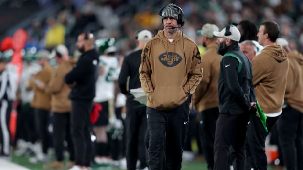New York Jets injured quarterback Aaron Rodgers walks down the sidelines during a game.
