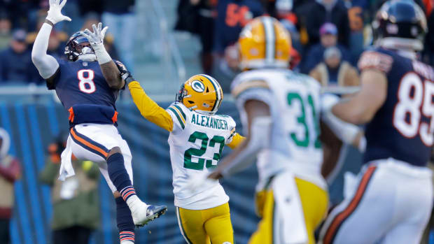 Jaire Alexander runs toward a Bears player as the ball is in the air