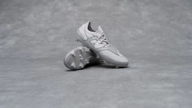 Side view of grey New Balance soccer cleats.