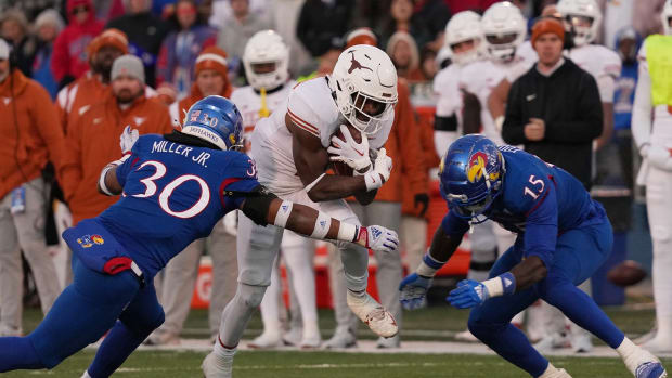 Texas Longhorns running back Keilan Robinson (7) carries the ball as Kansas Jayhawks linebacker Rich Miller (30) and Kansas Jayhawks linebacker Craig Young (15) defend.