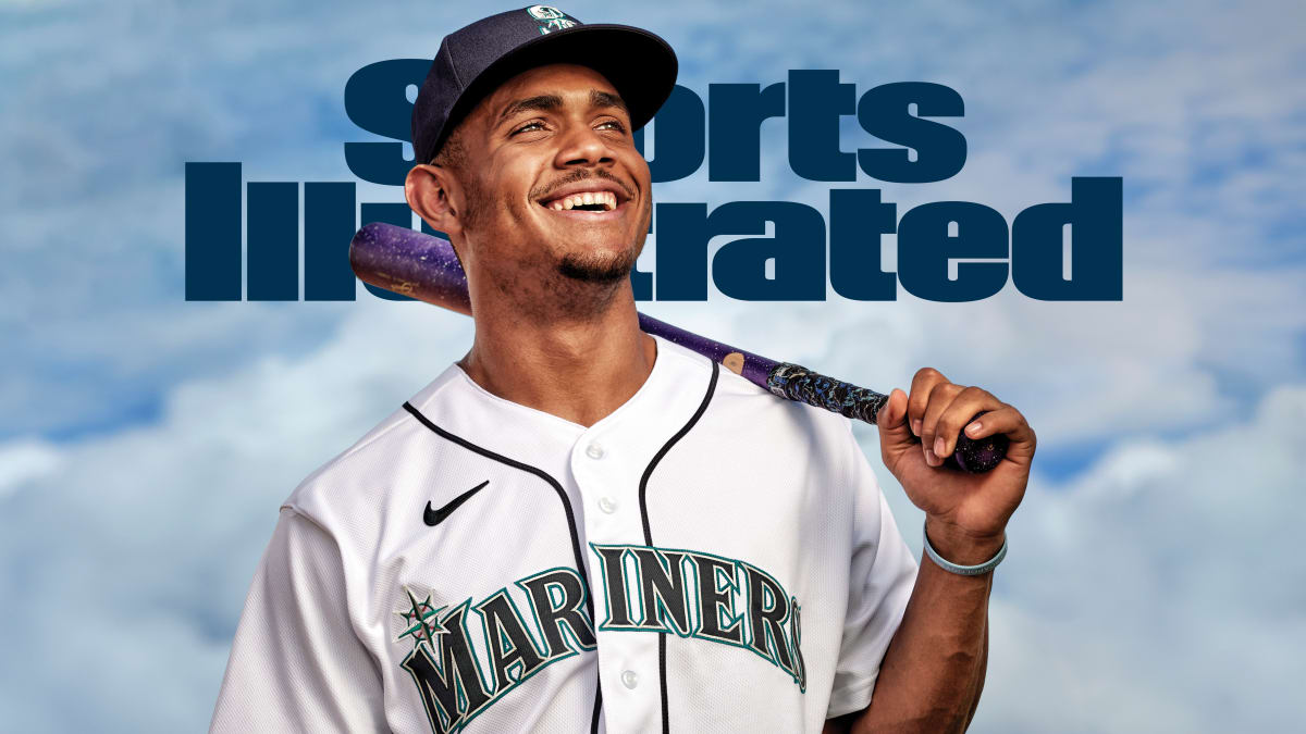 Seattle Mariners' Julio Rodriguez smiles as he speaks with a coach