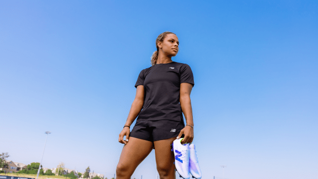 Michelle Cooper holds white and purple New Balance soccer cleats.