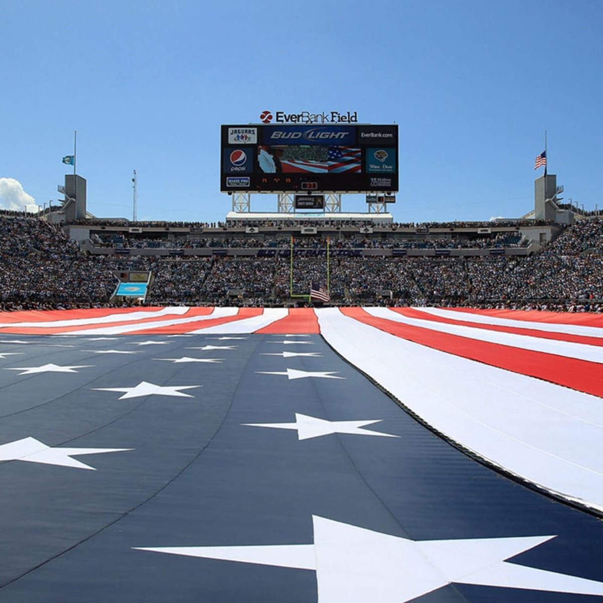 Men wave flags on the field before the start of an NFL football