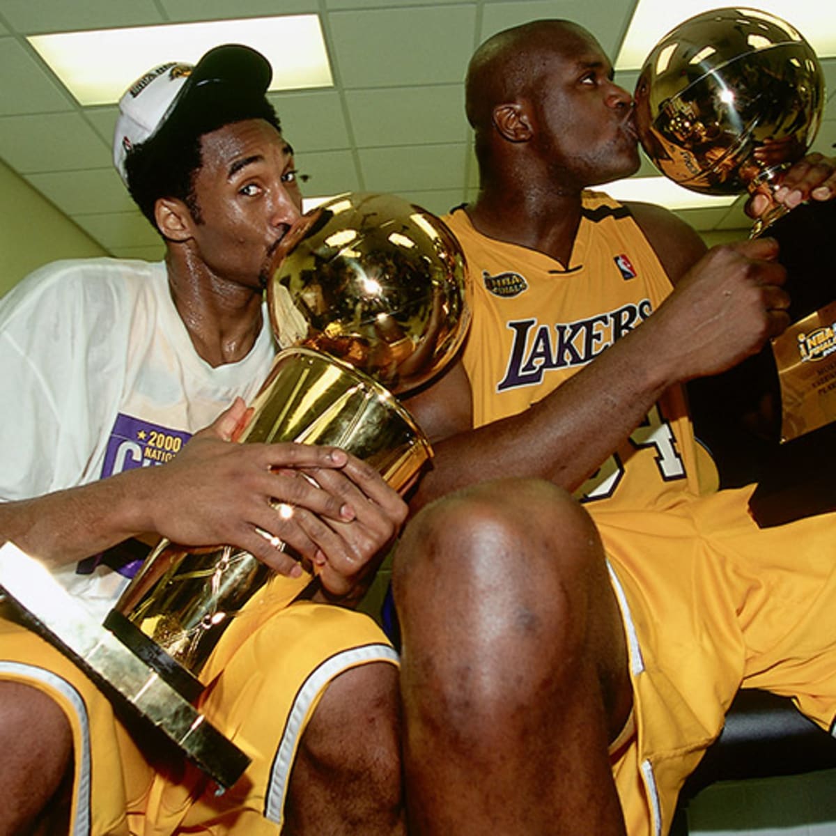Kobe Bryant holds both the Lakers 2010 NBA Championship trophy and the 2010 NBA  Finals trophy.