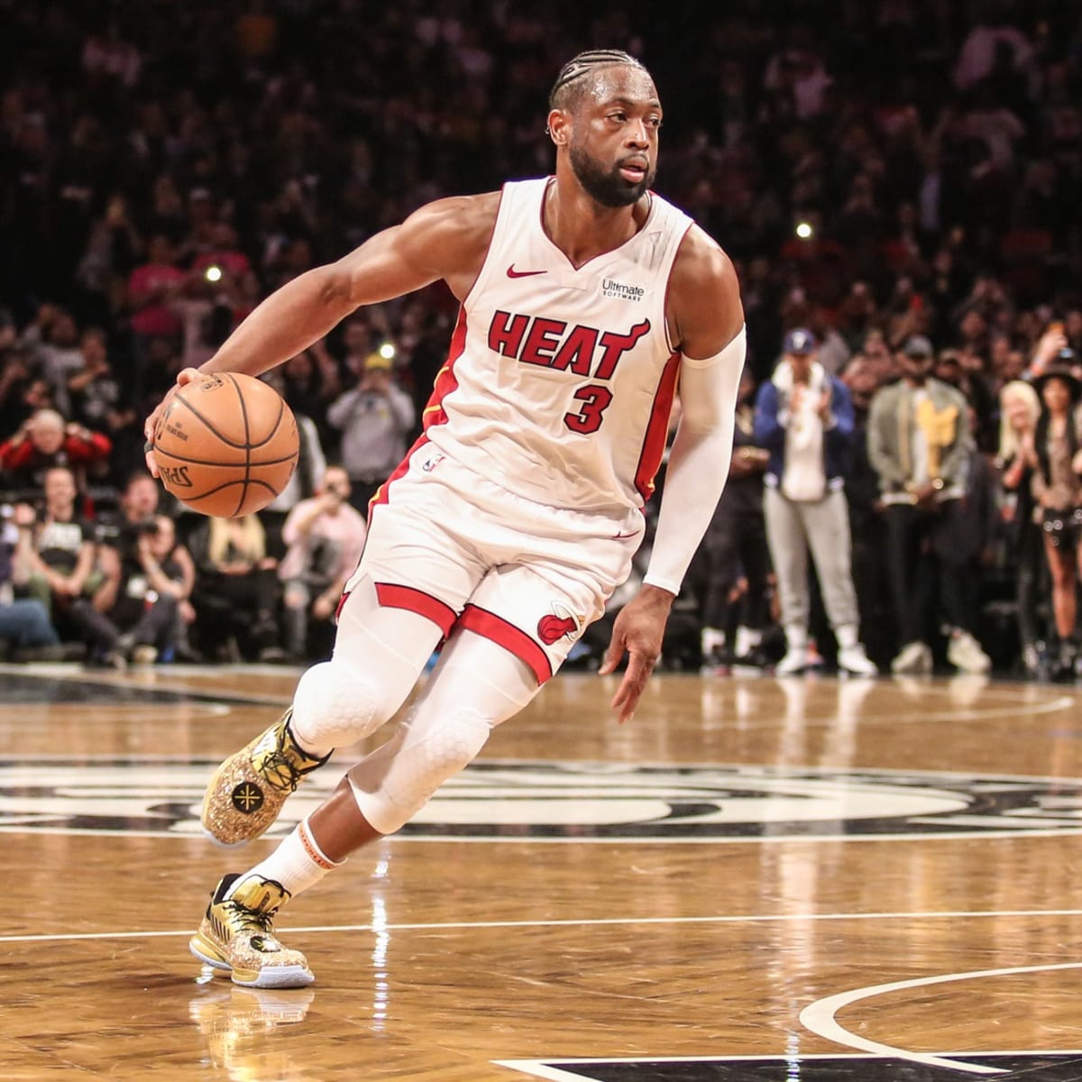 The Miami Heat's Dwyane Wade, left, holds a jersey with the number