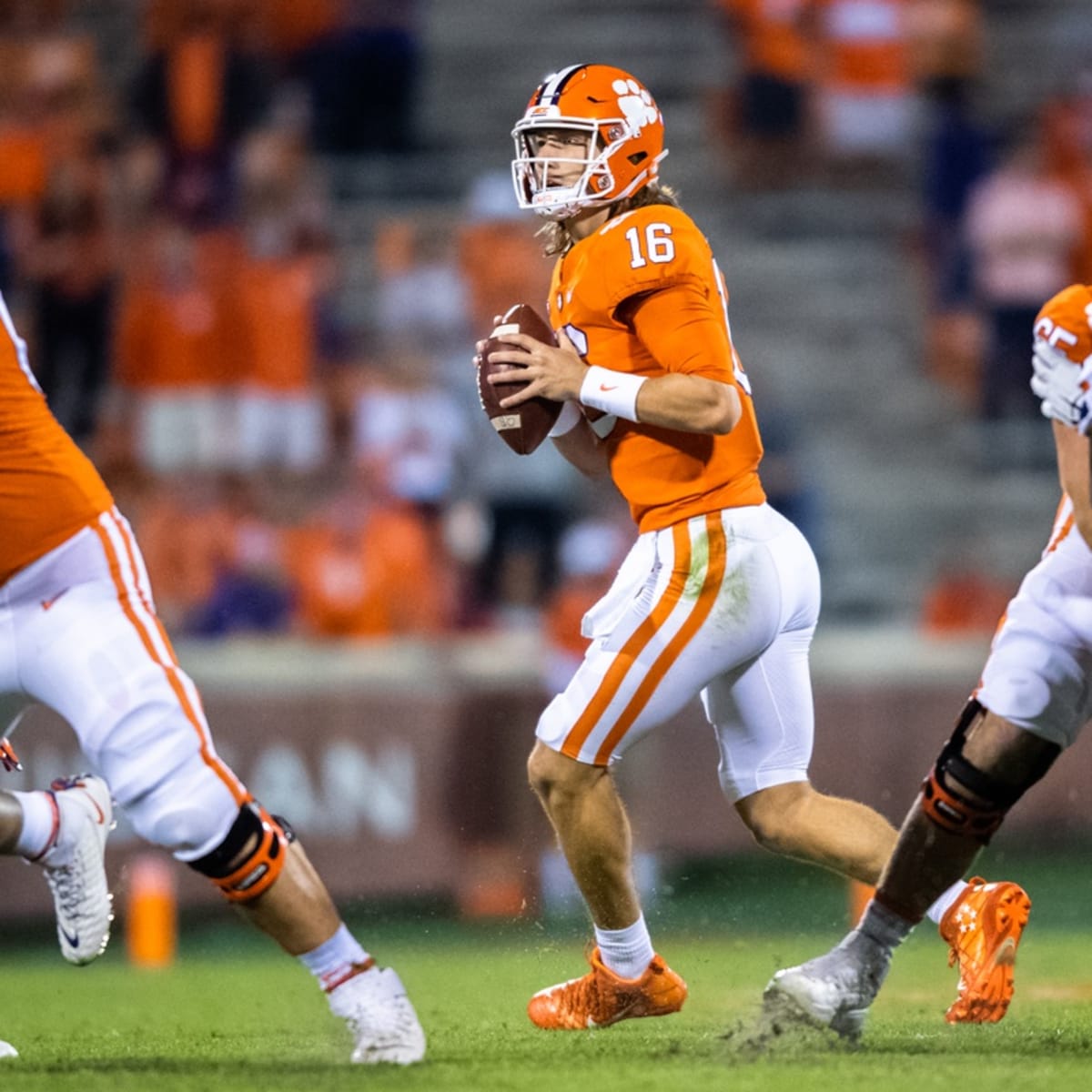 Clemson's Trevor Lawrence (16) hands the ball off to Travis Etienne (9)  during the first half of an NCAA college football game against North  Carolina State in Raleigh, N.C., Saturday, Nov. 9