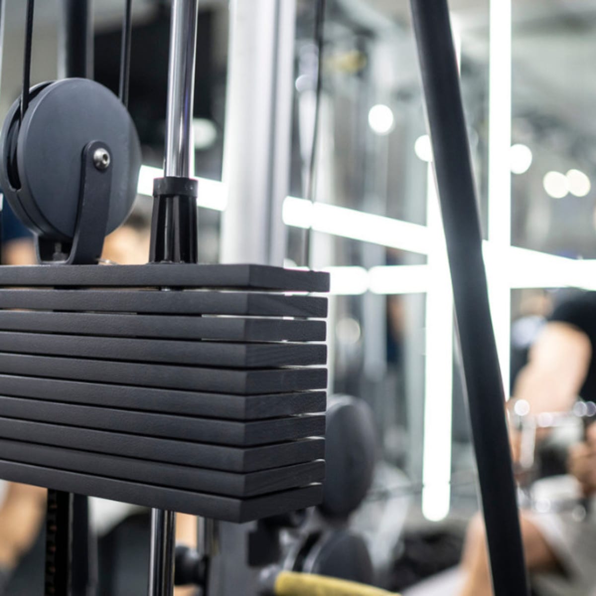 Professional woman athlete using the pulley machine Stock Photo by