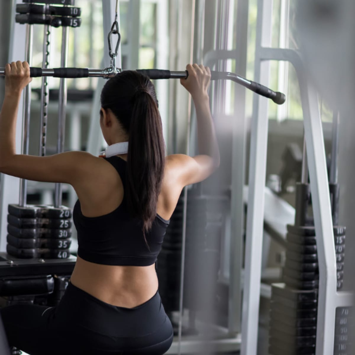 Professional woman athlete using the pulley machine Stock Photo by