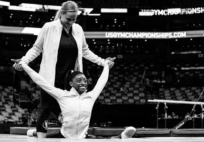 Biles stretching with a coach during an event at TD Garden in 2018.