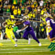 Oregon Ducks running back Bucky Irving stiff arms a Washington Huskies defender.