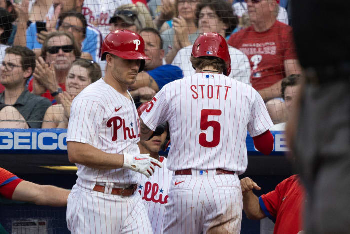 Bryson Stott returns to the dugout after scoring in the third inning, J.T. Realmuto looks on.