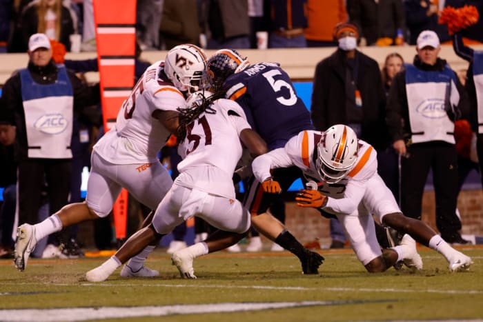 Virginia Cavaliers quarterback Brennan Armstrong (5) breaks the tackle of Virginia Tech Hokies defensive back Nasir Peoples (31), Hokies defensive back Armani Chatman (27), and Hokies defensive lineman TyJuan Garbutt (45) en route to a touchdown during the second quarter at Scott Stadium.