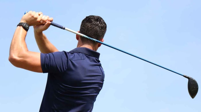 The deWiz Golf training aid is pictured on the wrist while a player swings a driver.