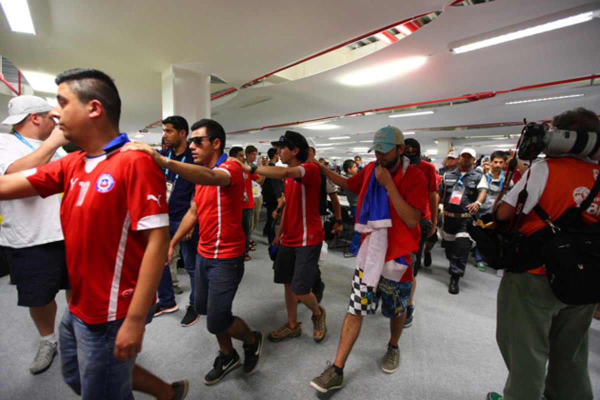 Chilean fans are led by Brazilian police and security personnel after breaking into Maracana Stadium before the start of their match against Spain. 