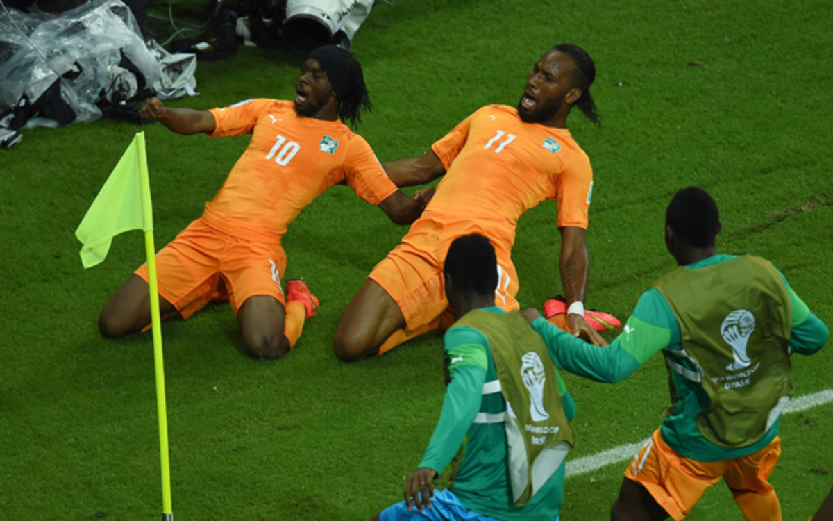 Gervinho, left, and Didier Drogba slide in unison toward the corner flag, where they are joined by their teammates after the former's game-winning goal in the Ivory Coast's 2-1 win over Japan.