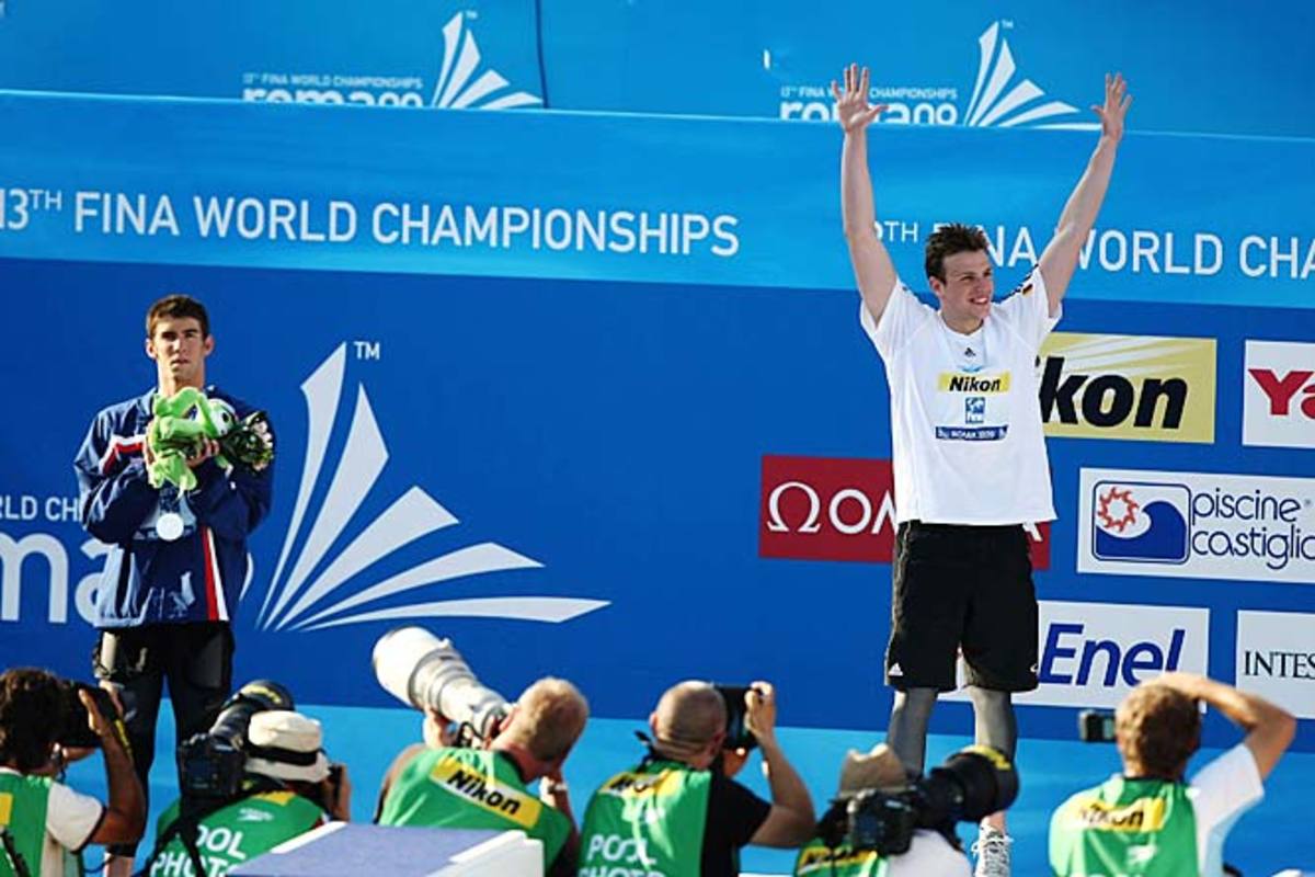 Michael Phelps stands to the side as Paul Biedermann celebrates