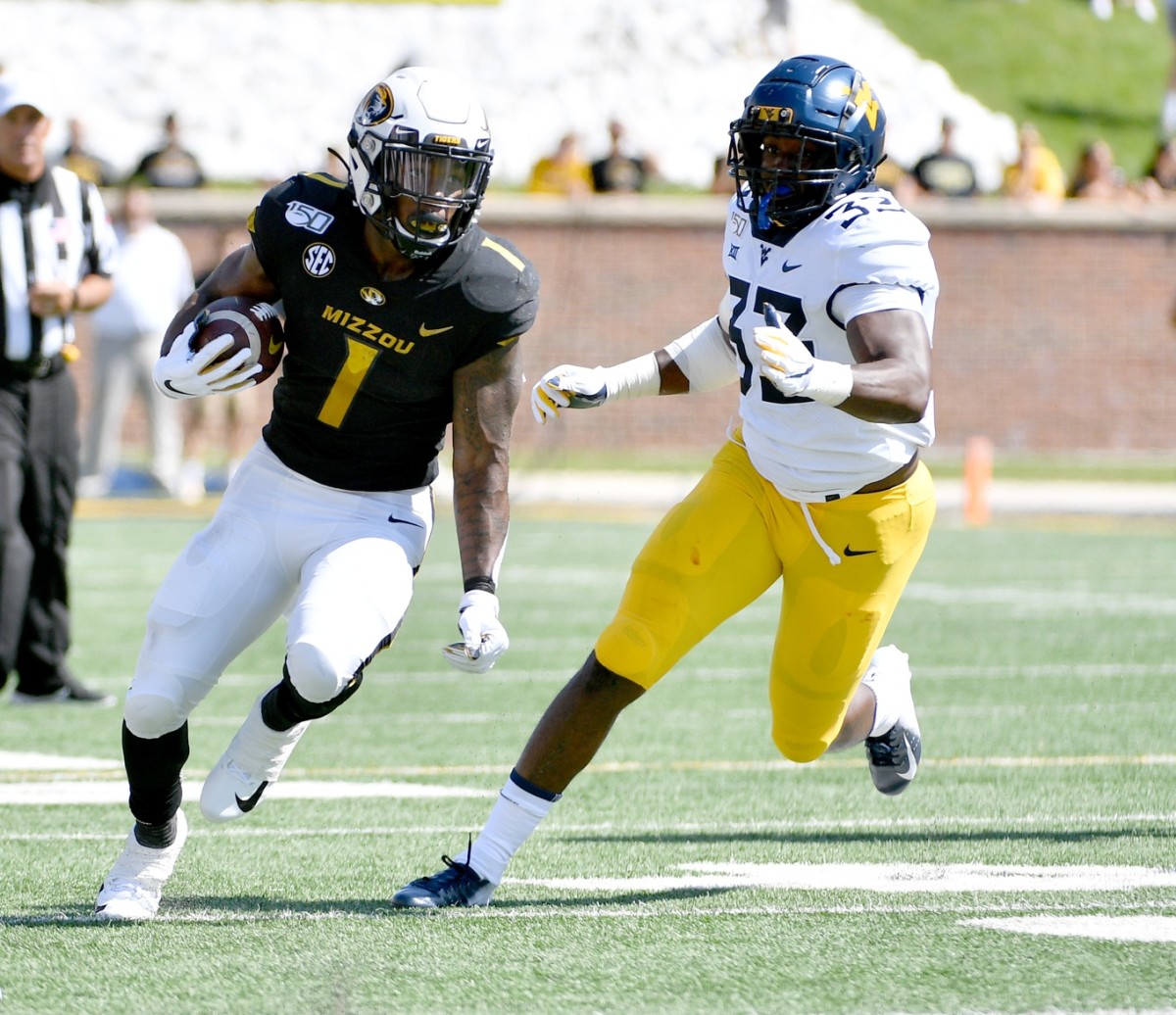 Missouri Tigers running back Tyler Badie (1) runs the ball as West Virginia Mountaineers linebacker VanDarius Cowan (32) attempts the tackle during the first half at Memorial Stadium/Faurot Field.