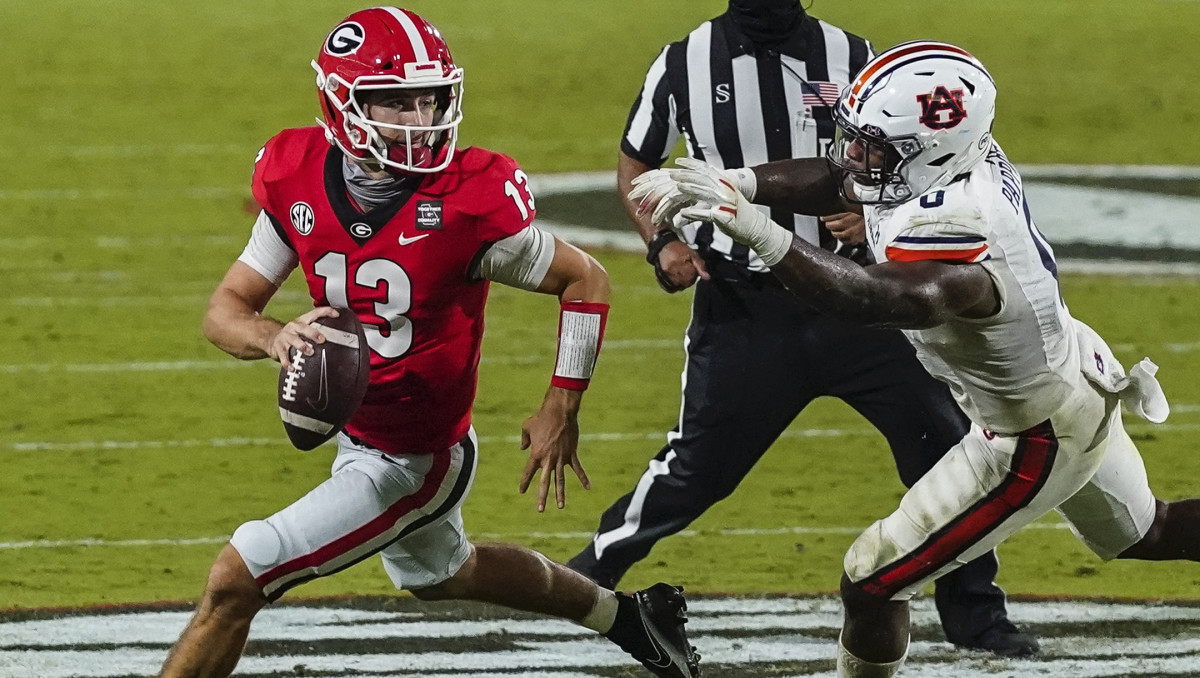 Georgia Bulldogs quarterback Stetson Bennett (13) escapes the pressure of Auburn Tigers Auburn Tigers linebacker Owen Pappoe (0) during the second half at Sanford Stadium.