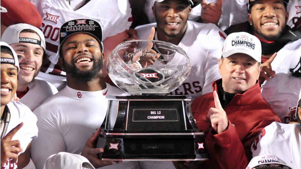 Eric Striker holding the Big 12 Championship Trophy with Bob Stoops