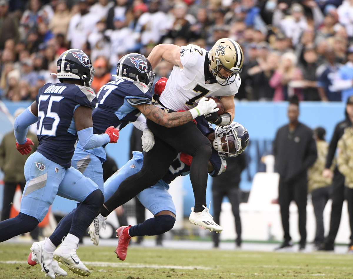 Nov 14, 2021; Nashville, Tennessee, USA; New Orleans Saints quarterback Taysom Hill (7) huddles through the tackle of Tennessee Titans safety Amani Hooker (37) and defensive back Chris Jackson (35) during the first half at Nissan Stadium. Mandatory Credit: Steve Roberts-USA TODAY Sports