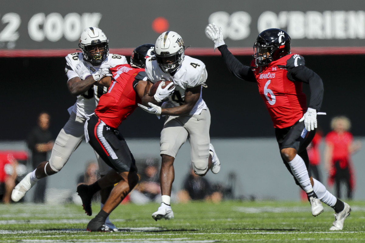 Oct 16, 2021; Cincinnati, Ohio, USA; UCF Knights wide receiver Ryan O'Keefe (4) runs with the ball against Cincinnati Bearcats cornerback Coby Bryant (7) and safety Bryan Cook (6) in the second half at Nippert Stadium. Mandatory Credit: Katie Stratman-USA TODAY Sports