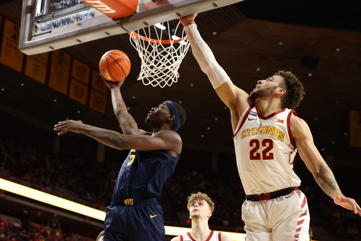 Feb 23, 2022; Ames, Iowa, USA; West Virginia Mountaineers forward Dimon Carrigan (5) scores in front of Iowa State Cyclones guard Gabe Kalscheur (22) at James H. Hilton Coliseum. Mandatory Credit: