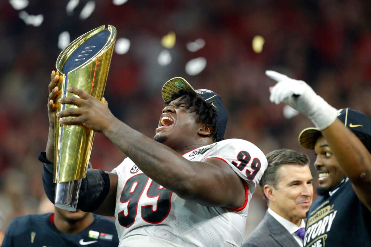 Georgia Bulldogs defensive lineman Jordan Davis (99) hoists the trophy Tuesday, Jan. 11, 2022, after defeating Alabama in the College Football Playoff National Championship at Lucas Oil Stadium in Indianapolis.