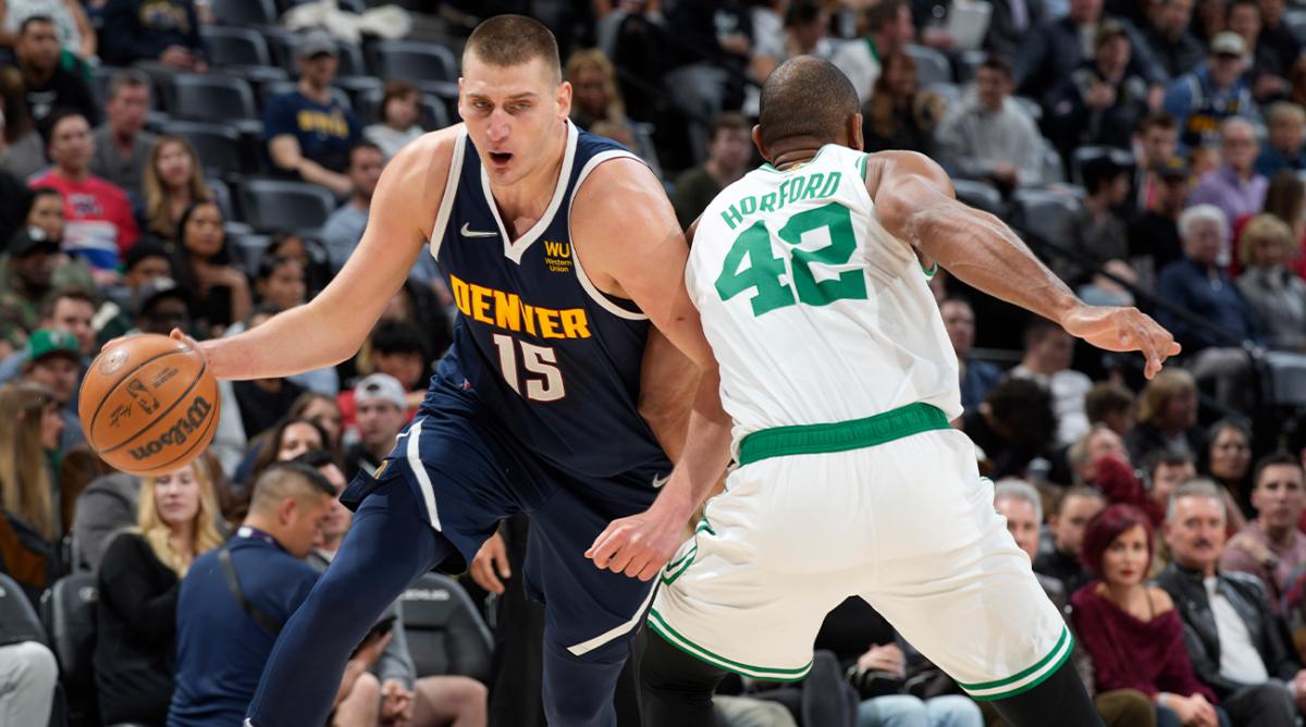 Denver Nuggets center Nikola Jokic, left, drives to the basket past Boston Celtics center Al Horford in the first half of an NBA basketball game Sunday, March 20, 2022, in Denver.