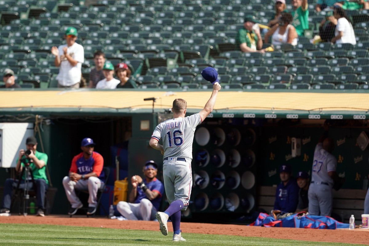 Texas Rangers third baseman Brock Holt (16) blows a bubble during a  baseball game against the