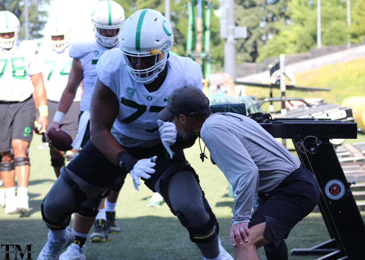 Offensive tackle George Moore strikes a blocking sled while Offensive Line Coach Alex Mirabal gives instruction.