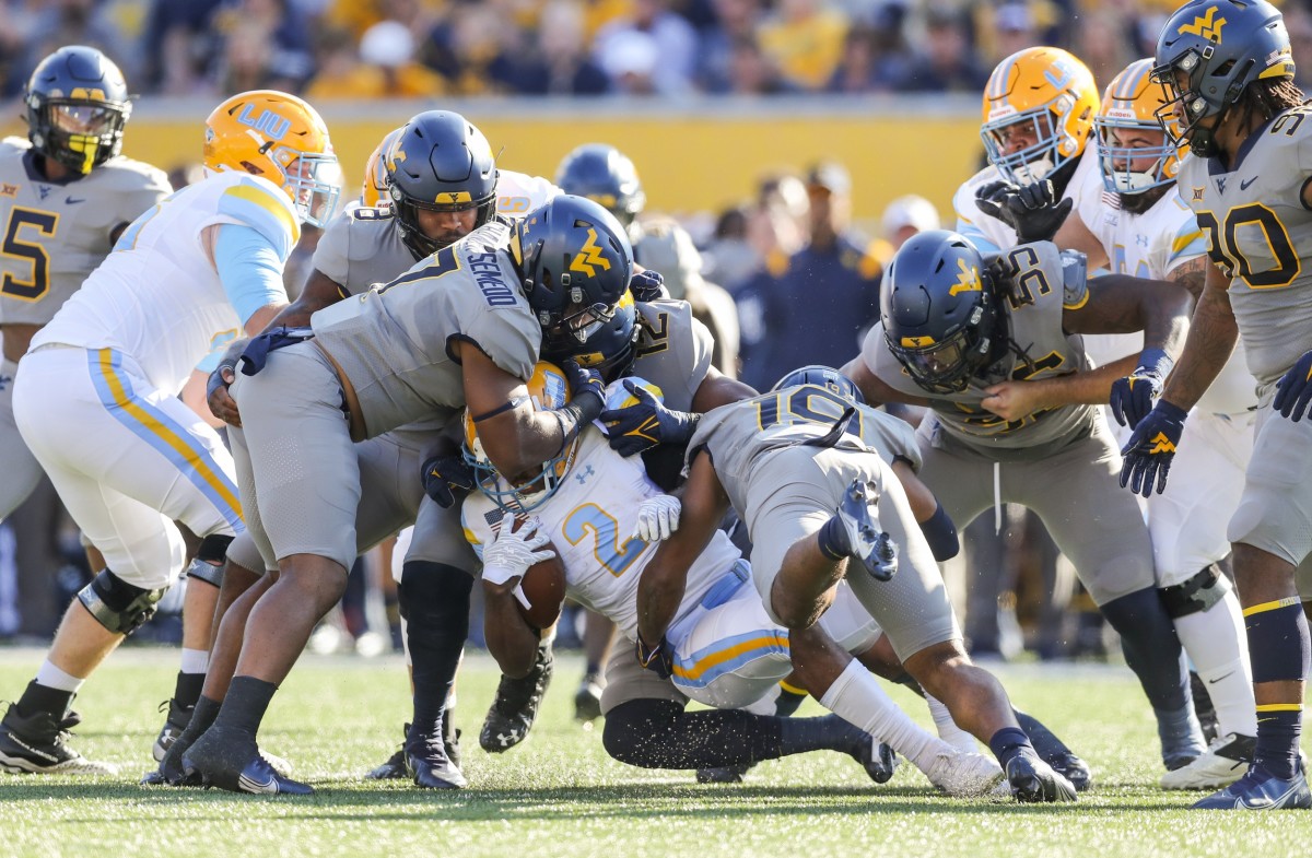 Sep 11, 2021; Morgantown, West Virginia, USA; Many West Virginia Mountaineers defenders tackle Long Island Sharks running back Jonathan DeBique (2) during the first quarter at Mountaineer Field at Milan Puskar Stadium.