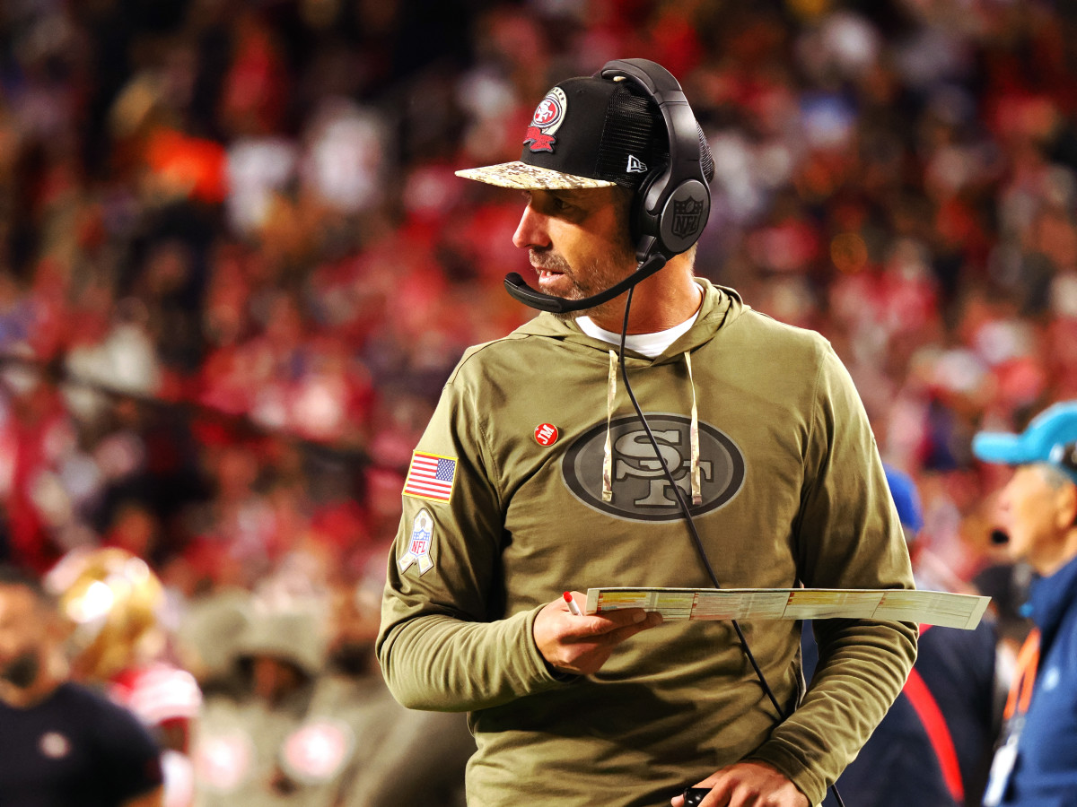 Kyle Shanahan looks to the field while holding his playsheet