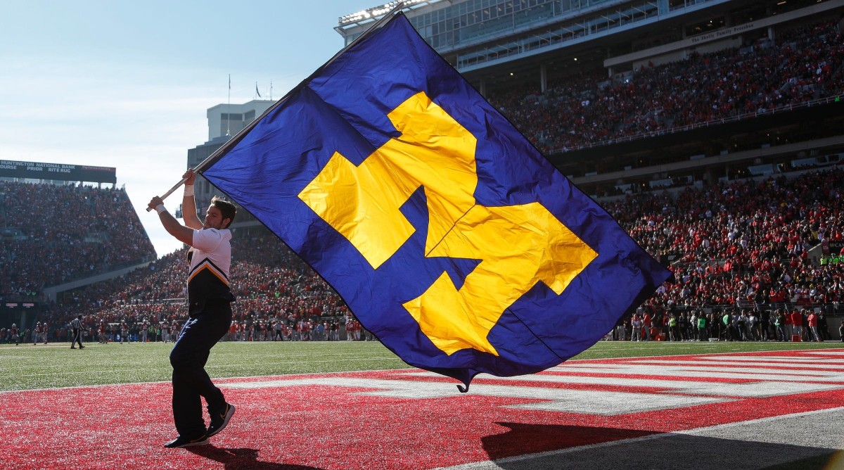 A Michigan cheerleader celebrates a touchdown against Ohio State by waving a Michigan flag.