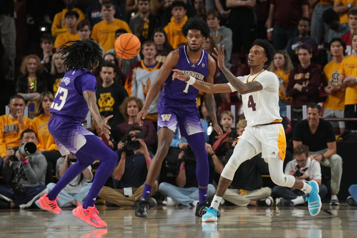 Demond Cambridge Jr. dishes a pass between the UW's Keyon Menifield and Keion Brooks.