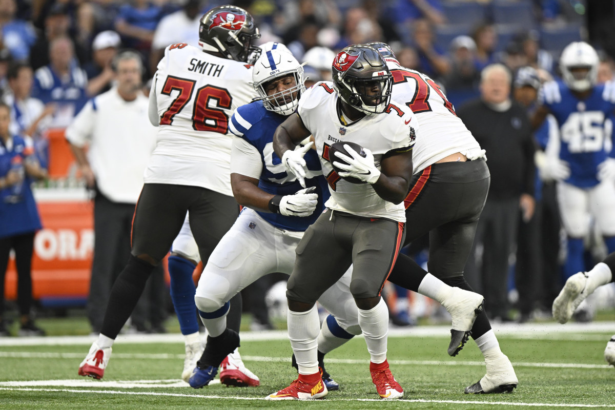 Aug 27, 2022; Indianapolis, Indiana, USA; Tampa Bay Buccaneers running back Leonard Fournette (7) tries to evade Indianapolis Colts defensive tackle Grover Stewart (90) during the first quarter of the game at Lucas Oil Stadium.