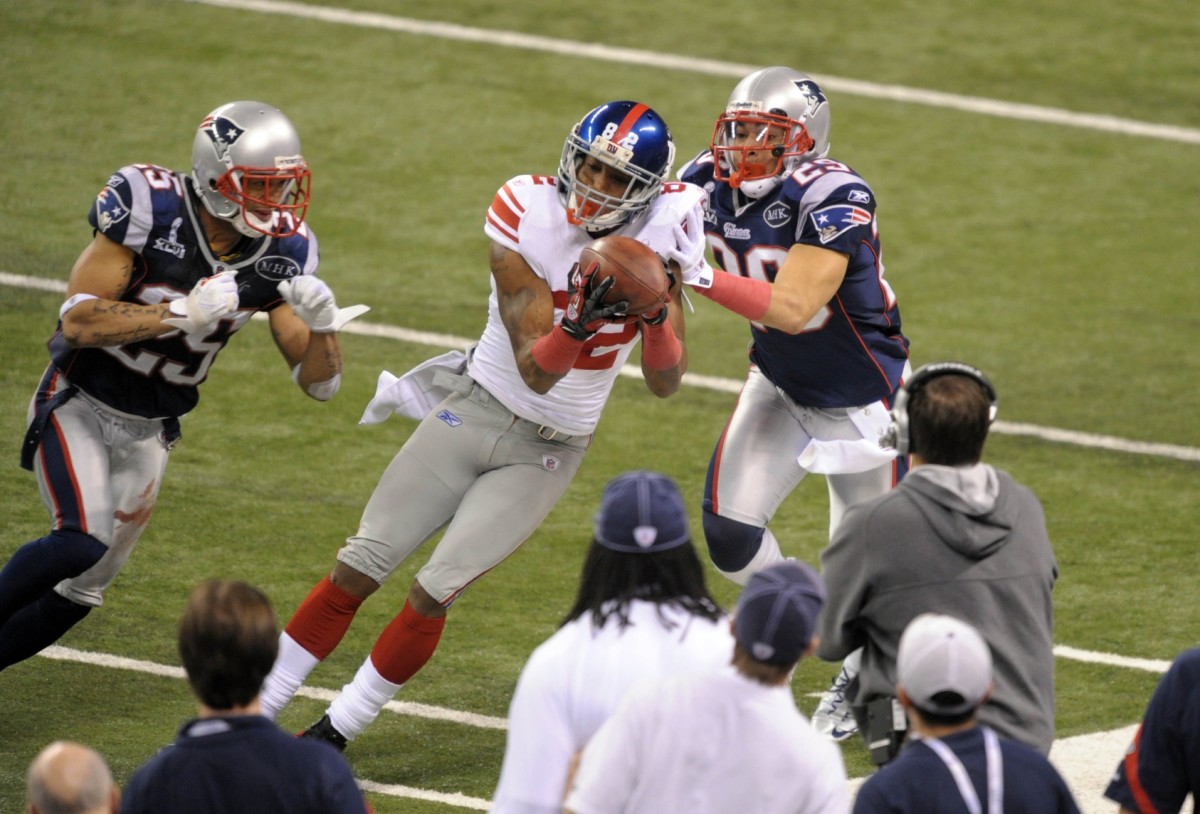 Feb 5, 2012; Indianapolis, IN, USA; New York Giants wide receiver Mario Manningham (82) makes a catch along the sideline in front of New England Patriots free safety Sterling Moore (29) and free safety Patrick Chung (25) in Super Bowl XLVI at Lucas Oil Stadium.