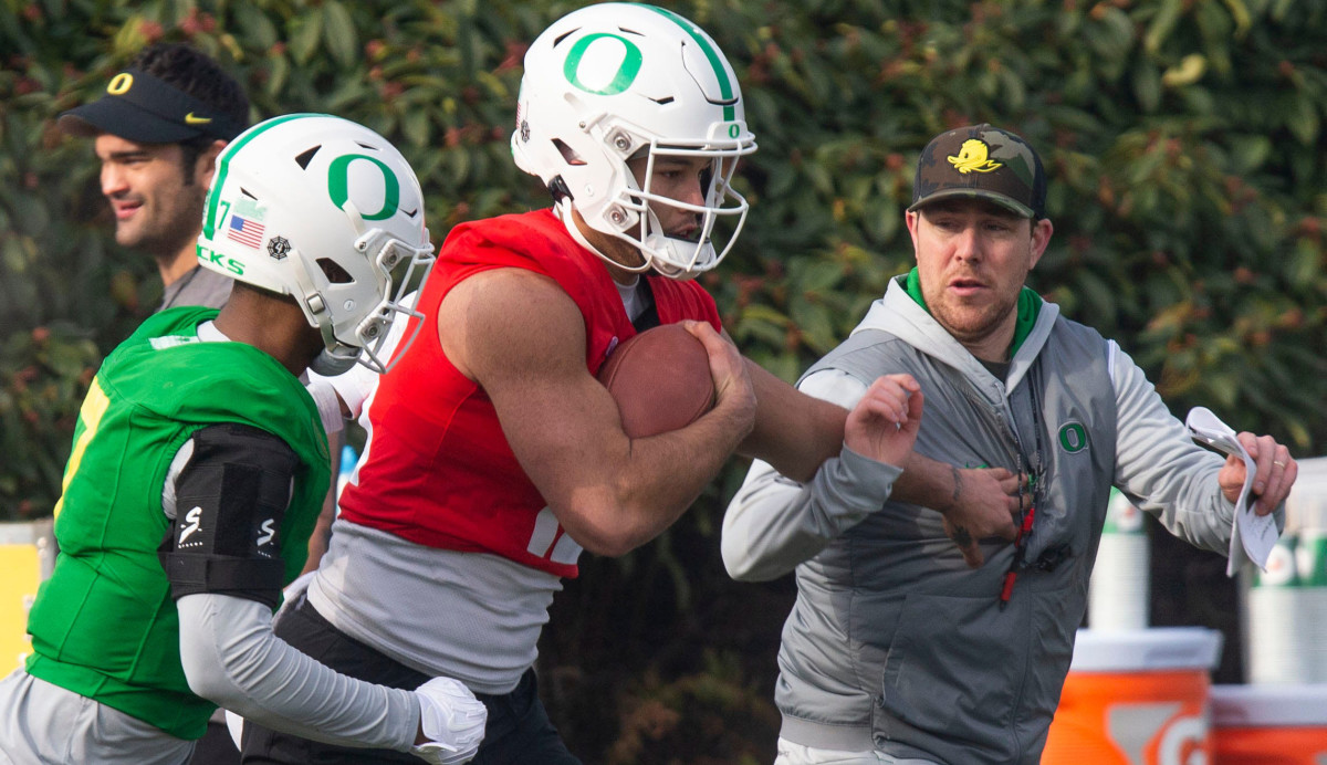 Oregon Ducks quarterback Ty Thompson goes through a ball security drill will offensive coordinator Will Stein.