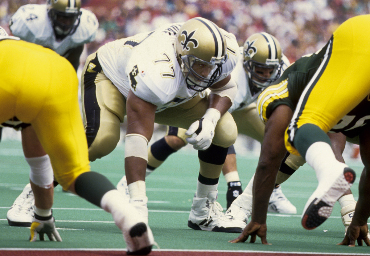 former New Orleans Saints offensive tackle Willie Roaf squats down to line up against the Packers, with one hand on the ground and one resting on his knee