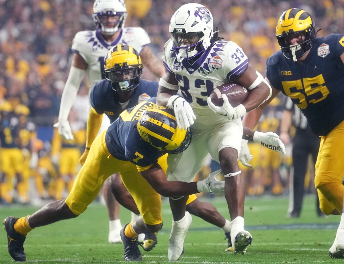 TCU running back Kendre Miller (33) tries to break away from Michigan Makari Paige (7) past during the 2022 Fiesta Bowl at State Farm Stadium. 2022-12-31-tcu-miller