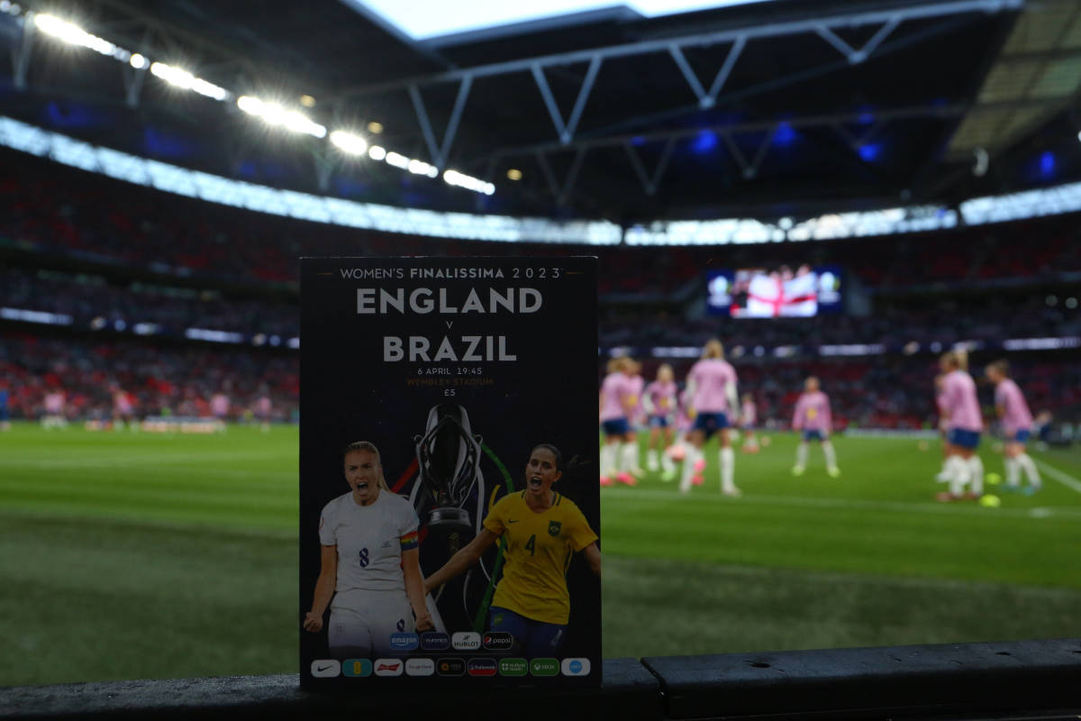 A photo taken before the first ever Women's Finalissima game in April 2023, showing a match program in the foreground at Wembley Stadium, where England played against Brazil