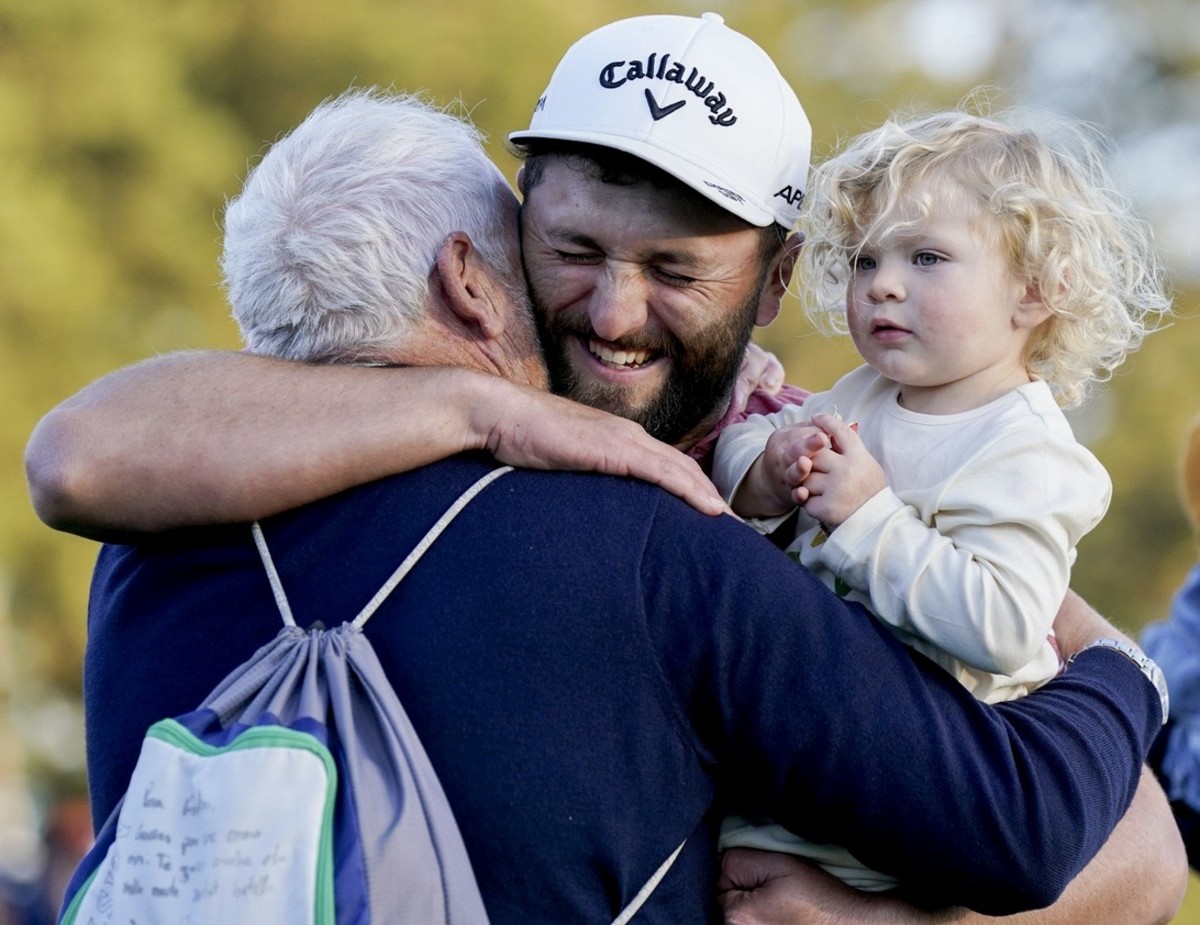 Victorious Jon Rahm shares a hug with his father and son.