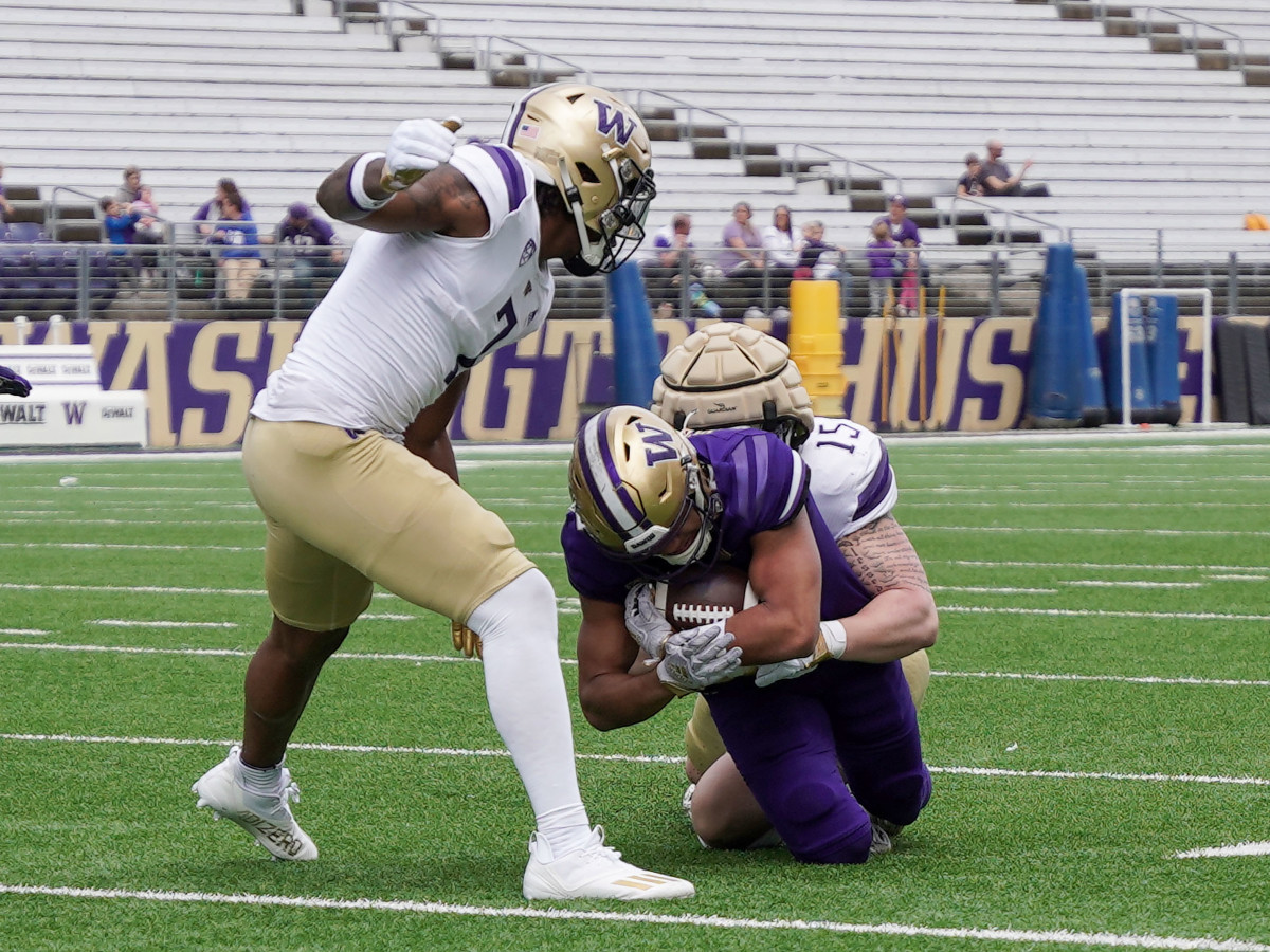 Edge rusher Zach Durfee makes a tackle, while safety Dom Hampton comes up to support.