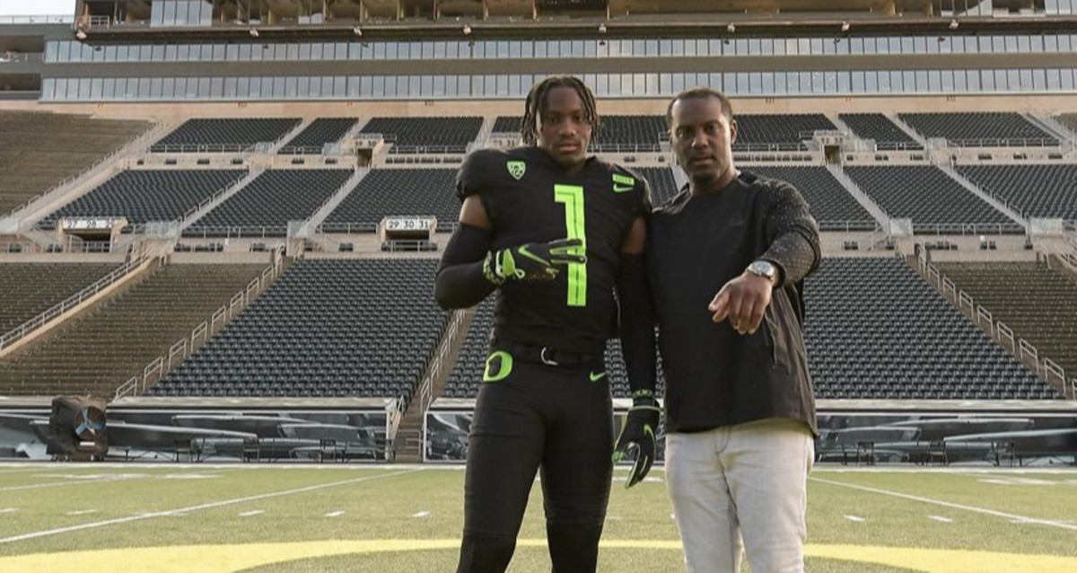 Jeremiah McClellan poses with wide receivers coach Junior Adams inside Autzen Stadium.